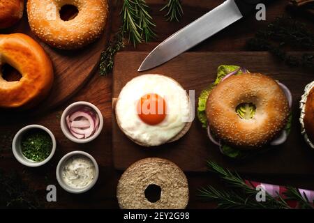 Assortimento di bagel freschi con diversi condimenti e ingredienti su sfondo di legno. Foto Stock
