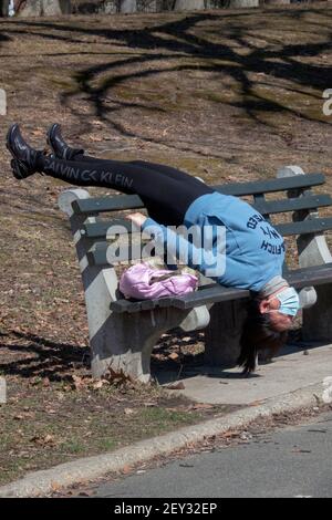 Una donna asiatica americana, probabilmente cinese, fa un tratto molto inusuale capovolto su una panchina in un parco a Queens, New York City Foto Stock