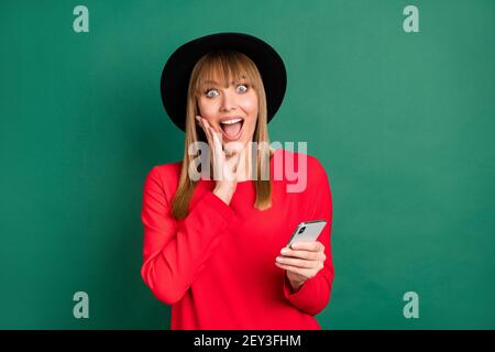 Foto di giovane attraente bella felice eccitato pazzo stupito ragazza vedi i piaci del mane nel telefono isolato su sfondo di colore verde Foto Stock