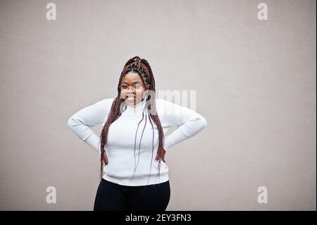 Donna afro-americana glamour in pullover bianco turleneck posa in strada. Foto Stock