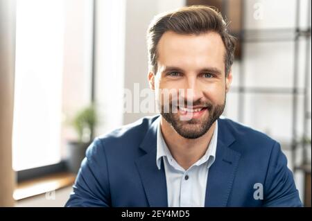 Elegante e moderno abbigliamento costoso stile di vita concetto persona. Primo piano ritratto fotografico di un elegante abito affilato con un uomo stoppie che guarda la fotocamera isolata, sullo sfondo dell'ufficio Foto Stock