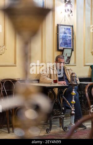 Ritratto candida di un uomo egiziano che fuma un tubo di narghilè all'interno di un caffè tradizionale (ahwa) al Cairo, Egitto Foto Stock