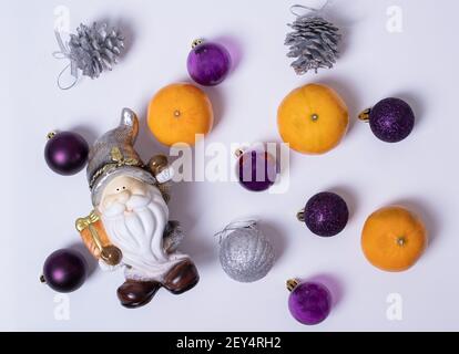 Composizione di Natale, Babbo Natale o gnome, regali di Natale, palline d'argento e coni, mandarino d'arancia su sfondo bianco, piatto, vista dall'alto, poliziotto Foto Stock