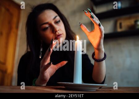 la ragazza sta indovinando su una candela illuminata e sulle schede, predicando il futuro e il destino Foto Stock