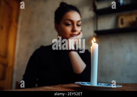 la ragazza sta indovinando su una candela illuminata e sulle schede, predicando il futuro e il destino Foto Stock