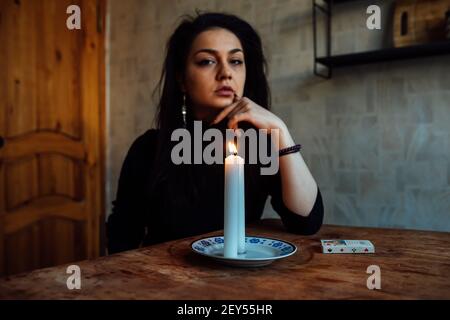 la ragazza sta indovinando su una candela illuminata e sulle schede, predicando il futuro e il destino Foto Stock