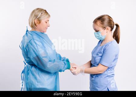 Foto in primo piano di una paziente femminile che si prende cura di sé e di una donna anziana che tiene le mani. Concetto di assistenza senior. Giovane medico femminile che tiene la mano della paziente femminile Foto Stock