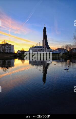 Una bella chiesa cattolica che si riflette in un lago mentre il il sole è ambientazione drammatica Foto Stock