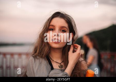 Ritratto della ragazza adolescente in piedi sul ponte al tramonto durante estate Foto Stock