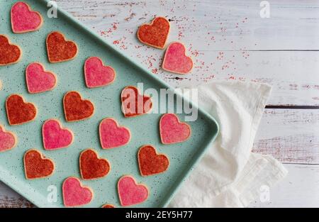 Sopra la padella di biscotti a forma di cuore appena sfornati su legno bianco. Foto Stock