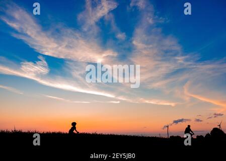un padre e un figlio che cavalcano le biciclette insieme al tramonto Foto Stock