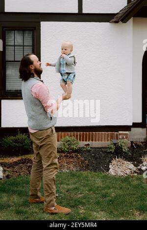 Divertimento papà giocare con bambino confuso figlio in cortile di fronte in primavera Foto Stock