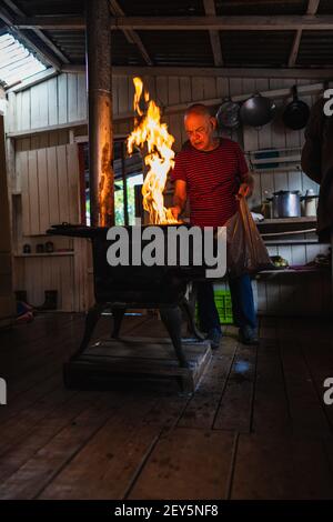 Uomo anziano che mette un po 'di legna in cucina per cucinare Foto Stock