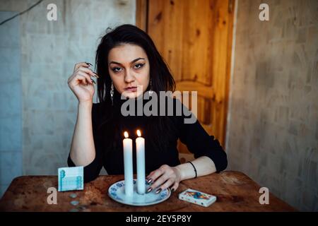 la ragazza sta indovinando su una candela illuminata e sulle schede, predicando il futuro e il destino Foto Stock