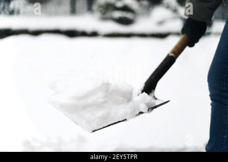 donna rimuove la neve dal suo cortile dopo una tempesta di neve, pala sn Foto Stock