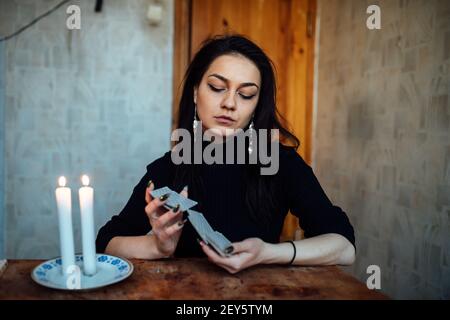 la ragazza sta indovinando su una candela illuminata e sulle schede, predicando il futuro e il destino Foto Stock