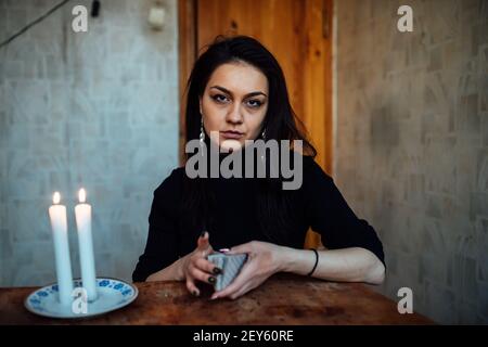 la ragazza sta indovinando su una candela illuminata e sulle schede, predicando il futuro e il destino Foto Stock