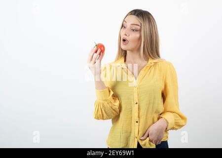 Immagine di una donna sorpresa che guarda il pomodoro rosso su bianco sfondo Foto Stock