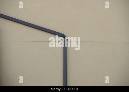 tubo di scarico in metallo per lo scarico dell'acqua per la pioggia acqua contro parete esterna di calcestruzzo di casa o edificio pulito righe spazio parete vuoto per tipo Foto Stock