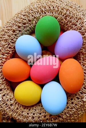 Immagine verticale di un cesto intessuto pieno di Pasqua colorata Uova Foto Stock