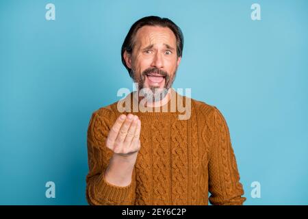 Ritratto fotografico di un uomo stressato seccato che sostiene di indossare le mani gesturanti pullover in maglia marrone isolato su sfondo di colore blu brillante Foto Stock