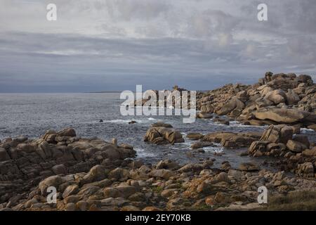 Una vista affascinante dell'oceano che colpisce la costa rocciosa luccicante sotto lo sk nuvoloso Foto Stock