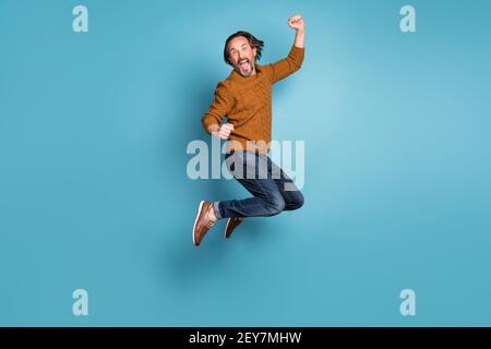 Foto a dimensione intera di un bell'uomo sorridente pazzo eccitato salto in vittoria di successo isolato su sfondo blu Foto Stock