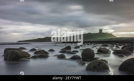 Una lunga esposizione immagine del castello di Dunstanburgh come un un lampo di luce sparato attraverso le nuvole Foto Stock