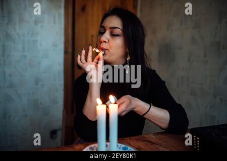 una ragazza fortuna teller accende candele per predire il futuro. rituale mistico di comunicazione con gli spiriti Foto Stock