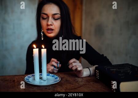 una ragazza fortuna teller accende candele per predire il futuro. rituale mistico di comunicazione con gli spiriti Foto Stock