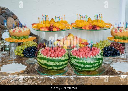 Affettare la frutta in un banchetto di nozze. Anguria, uva, fragola, arancio, prugna, pera, dinha, pesca, kiwi, ananas, persimmon, mela Foto Stock