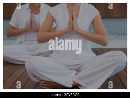 Sezione centrale di due donne caucasiche che praticano yoga meditando seduto sopra pavimento Foto Stock