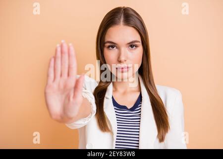 Foto della mano della giovane signora calmo che mostra il segnale di stop indossare bianco blazer isolato colore beige pastello sfondo Foto Stock