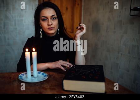 una ragazza fortuna teller accende candele per predire il futuro. rituale mistico di comunicazione con gli spiriti Foto Stock