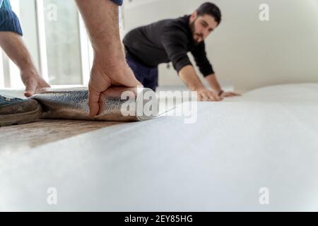 Due uomini che installano il laminato per pavimento per l'installazione di un pavimento in legno nella ristrutturazione di una casa Foto Stock