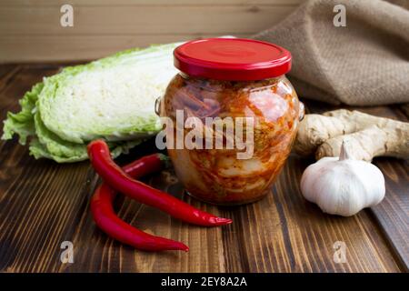 Kimchi nel vaso di vetro e ingredienti sul rustico sfondo di legno Foto Stock