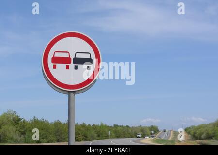 Il sorpasso è vietato sulla segnaletica stradale rotonda. Avvertenza per i conducenti su un tratto di strada pericoloso. Foto Stock