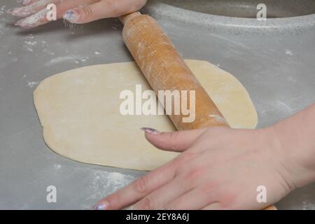 Cuocete l'impasto con il mattarello di legno. Fare pizza o gnocchi fatti in casa. Primo piano, messa a fuoco selettiva. Foto Stock