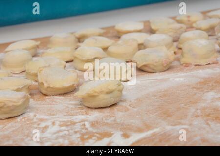 Gnocchi fatti in casa primo piano a bordo con farina. Preparazione dei ravioli per l'ebollizione. Primo piano, messa a fuoco selettiva, profondità di campo poco profonda. Foto Stock