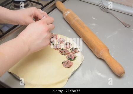 Cook fa gnocchi fatti in casa. Mettere la carne macinata sull'impasto di farina. Primo piano, messa a fuoco selettiva. Foto Stock