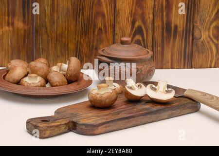 Processo di cottura dei funghi. Royal champignons marrone affettato ​​on tagliere di legno. Foto Stock