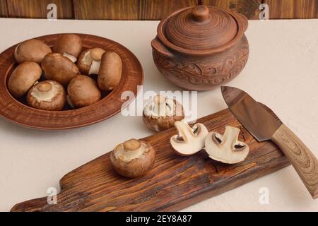 Champignon marroni per la cottura al forno. I funghi sono tritati sul taglio di tavola di legno. Foto Stock