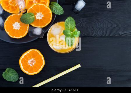 Limonata fredda con mandarini o arance su fondo di legno nero. Vista dall'alto. Spazio di copia. Foto Stock