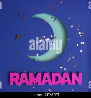 Luna di Crescent taglio di carta su uno sfondo glitter e parola di carta Ramadan. Modello per Eid al-Adha Mubarak o Kurban Bairam. Foto Stock