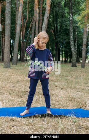 Educazione ambientale per i bambini. Bambina che tiene la pianta giovane in mani contro sfondo albero verde. Ambiente, sostenibilità, giorno della terra Foto Stock