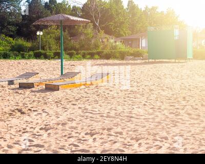 Spiaggia. Tre letti sotto l'ombrello. Green spogliatoio sullo sfondo del cottage Foto Stock