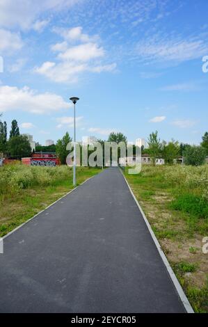 POZNAN, POLONIA - 09 luglio 2017: Strada asfaltata lungo le erbacce verdi nel parco Rataja Foto Stock