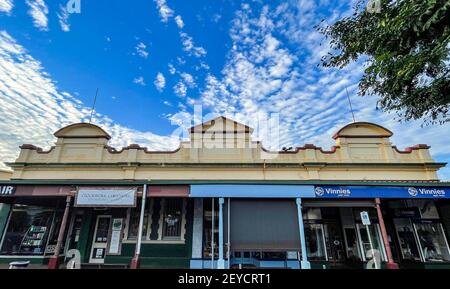 Bella fila di negozi, costruita dal 1893 al 1930, nel pittoresco paesaggio urbano della strada principale di Childers, regione di Bundaberg, Queensland, Australia Foto Stock