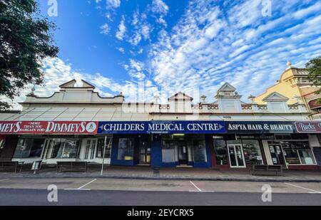 Bella fila di negozi, costruita dal 1902 al 1907, nel pittoresco paesaggio urbano della strada principale di Childers, regione di Bundaberg, Queensland, Australia Foto Stock