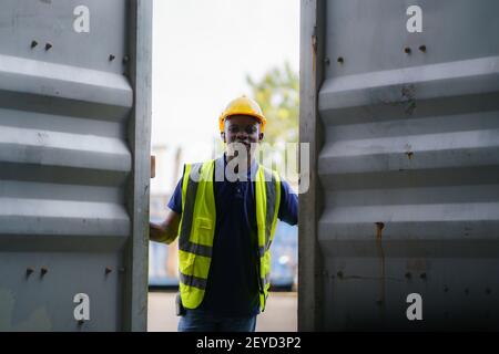 I lavoratori neri afroamericani stanno aprendo i contenitori per l'ispezione e controllano che le riparazioni siano state completate nel terminal dei contenitori. Foto Stock